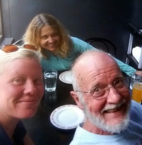 Three people sit at a tabl, smiling toward the camera