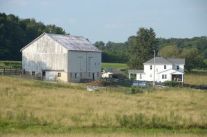 A wide landscape shows a farm with fields, barns and outbuildings, and a farmhouse, built before 1860